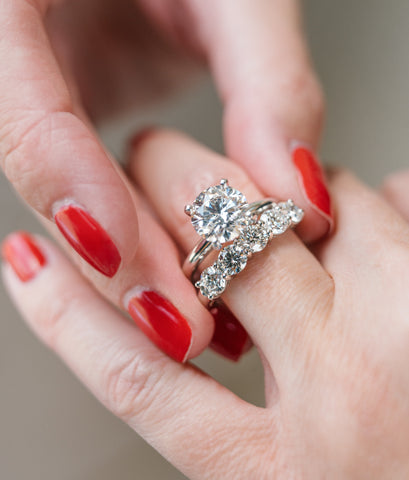 Woman putting on diamond wedding and engagement rings