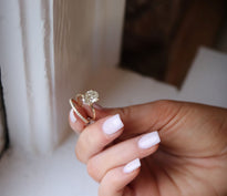 Woman holds diamond wedding band and solitaire engagement ring