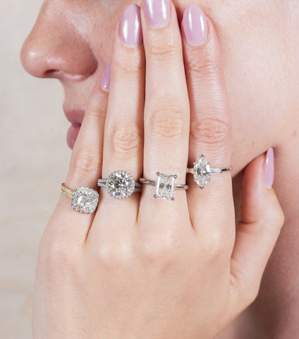 woman wearing four different engagement rings with various diamond shapes