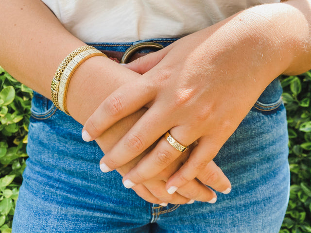 person wearing jeans with hands crossed over each other wearing jewelry