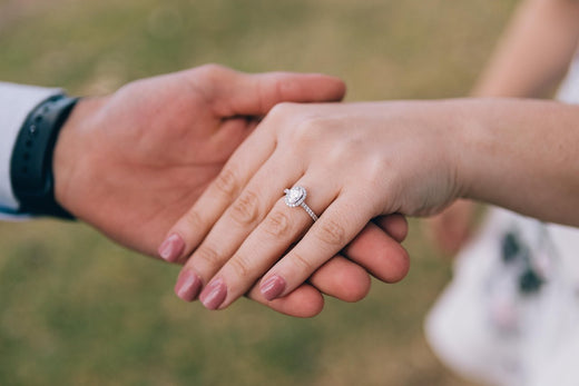 Man holding woman's hand with diamond engagement ring