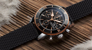 Luxury Breitling watch with black strap sitting on wood table